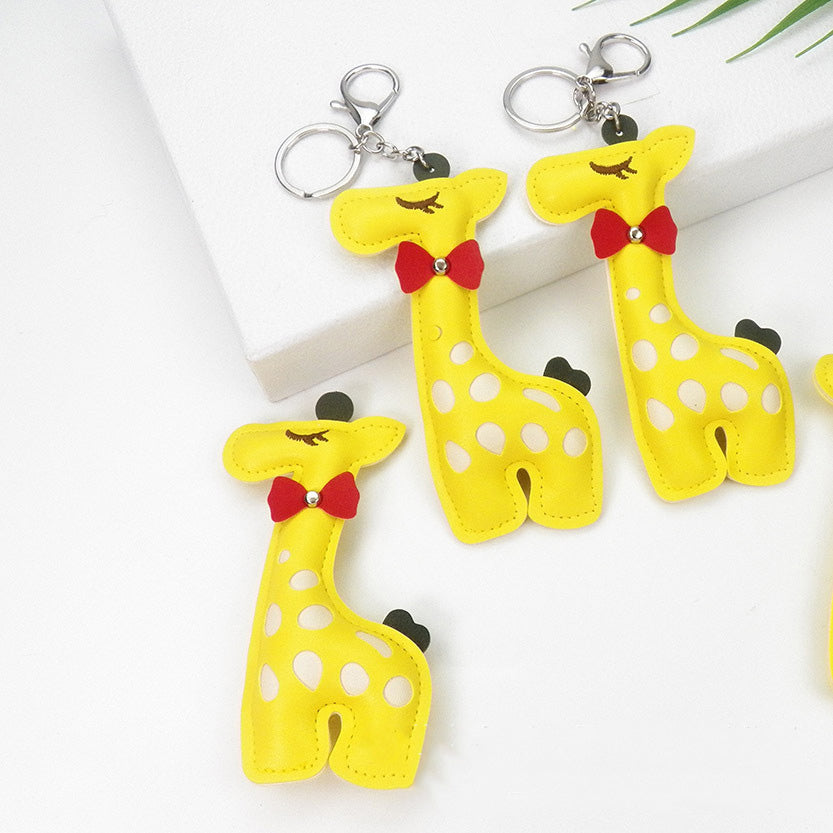 Close-up of adorable yellow PU leather giraffe keychains with white polka dots, red bows, and charming details.