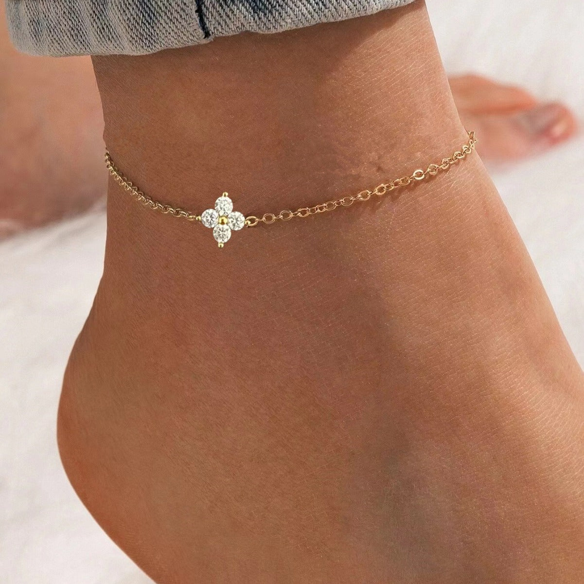 A woman wearing the gold-plated 925 silver four-leaf clover anklet, showcasing its delicate design and sparkling CZ crystals on her ankle.