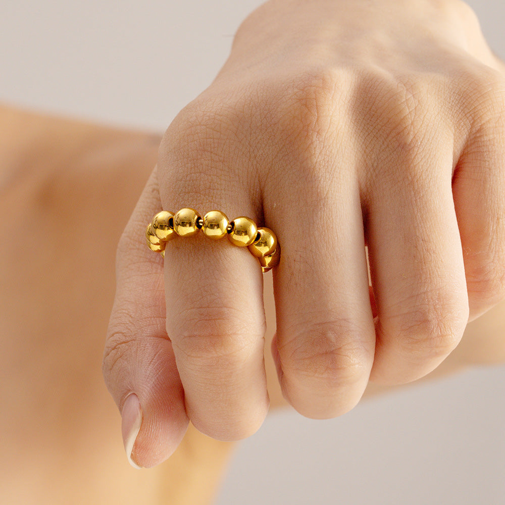 A model's hand wearing the adjustable stainless steel punk bead ball ring in a gold finish, showcasing its elegant design.