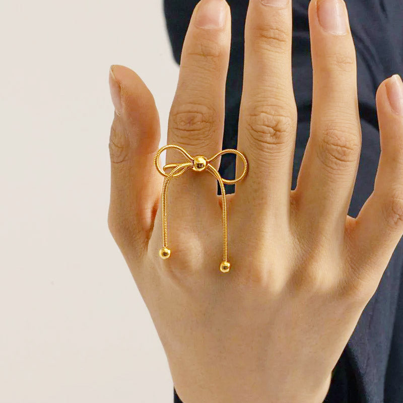 A close-up of the stainless steel gold PVD bowknot adjustable ring, showcasing its intricate bow design and dangling details.