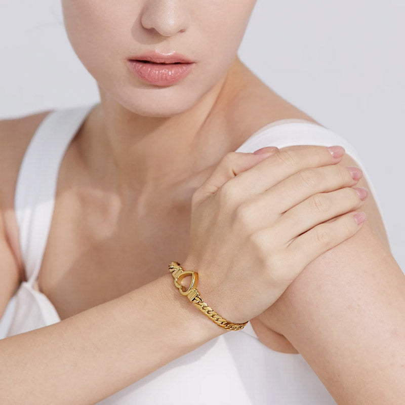 A model wearing the gold-tone stainless steel chunky Cuban chain bracelet with a hollow-out heart charm.