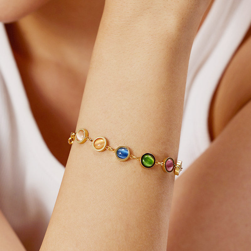 A close-up of a gold-plated stainless steel link chain bracelet adorned with vibrant, colorful natural opal stones, on a clean white background.