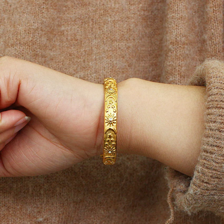 A close-up of the 18k gold-plated stainless steel bracelet from the sun and moon set, featuring intricate celestial designs with white cubic zirconia accents.