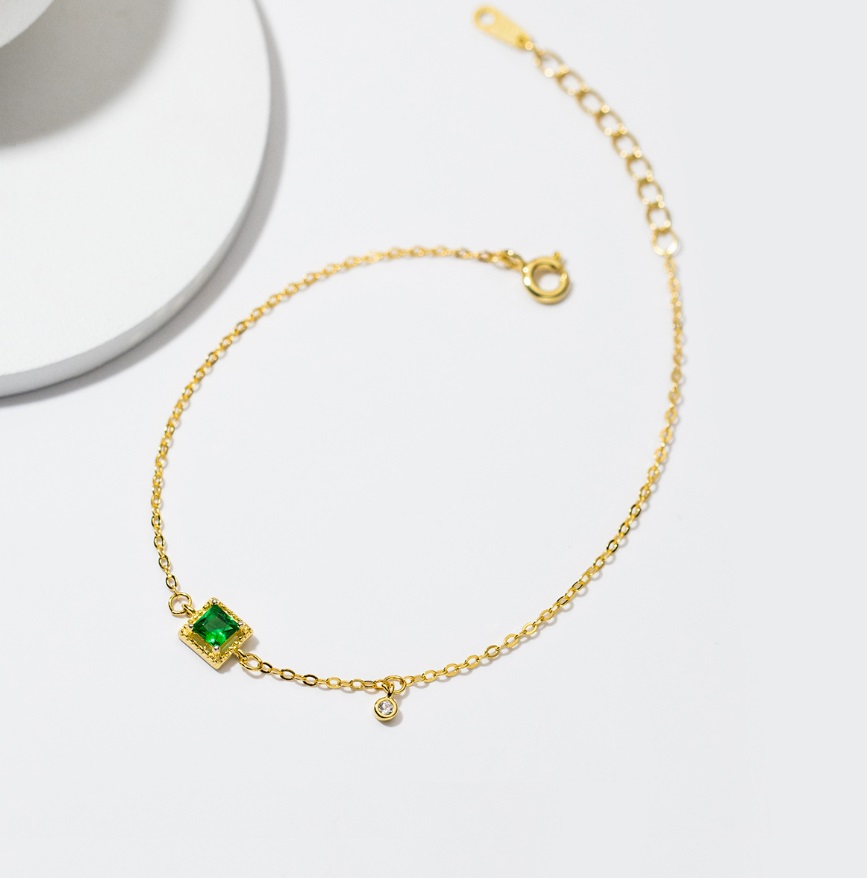 A close-up of the 925 Sterling Silver Emerald Gold Plated Bracelet, showcasing the green emerald and clear cubic zirconia gemstones on a gold chain.
