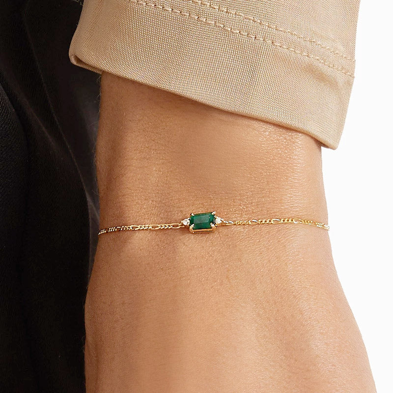 A detailed view of a gold-plated 925 sterling silver Figaro chain bracelet, centered with a brilliant rectangular emerald-green zircon.