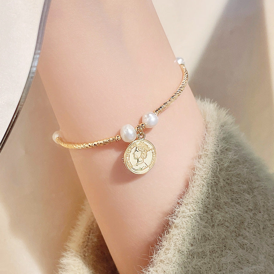 A 14K gold-plated bracelet from a set of five, featuring natural freshwater pearls and a classic queen's head coin charm on a white background.