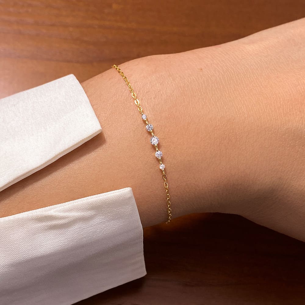 A close-up of the 925 Sterling Silver Dainty Cubic Zirconia Chain Bracelet in gold, worn on a wrist to showcase its delicate design.