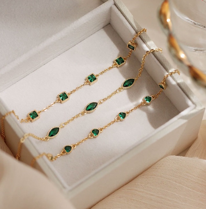 A set of three 925 Sterling Silver Emerald Bracelets with gold plating, featuring vibrant green cubic zirconia, displayed elegantly in a white jewelry box.
