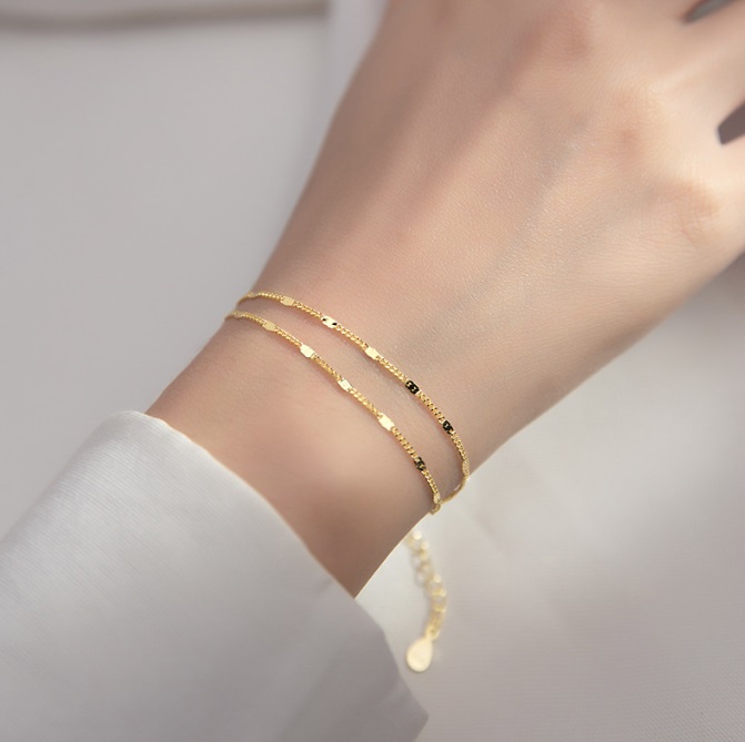 A close-up view of the 925 Sterling Silver Gold Link Chain Bracelet elegantly worn on a wrist, showcasing its intricate link design and radiant gold finish.