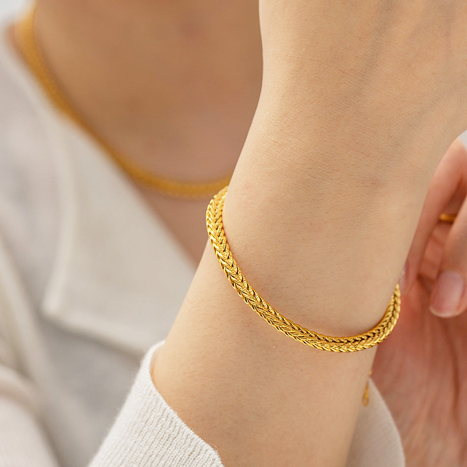 A close-up view of a person wearing the gold-plated stainless steel retro wide curb chain bracelet, showcasing its detailed design.