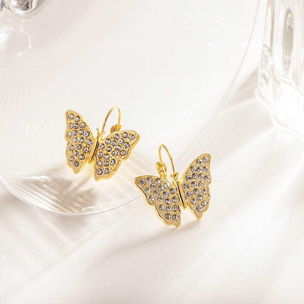 A pair of stainless steel gold zircon butterfly drop hook earrings with sparkling clear gemstones on a white background.