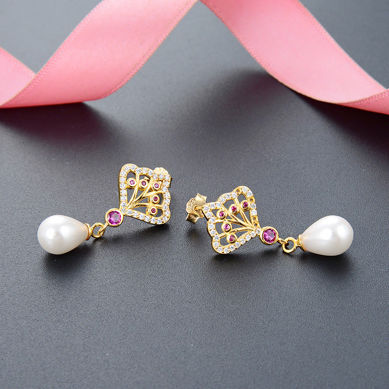 A close-up of a pair of 925 sterling silver, gold-plated princess style earrings featuring a butterfly design with pink gemstones and a dangling pearl.