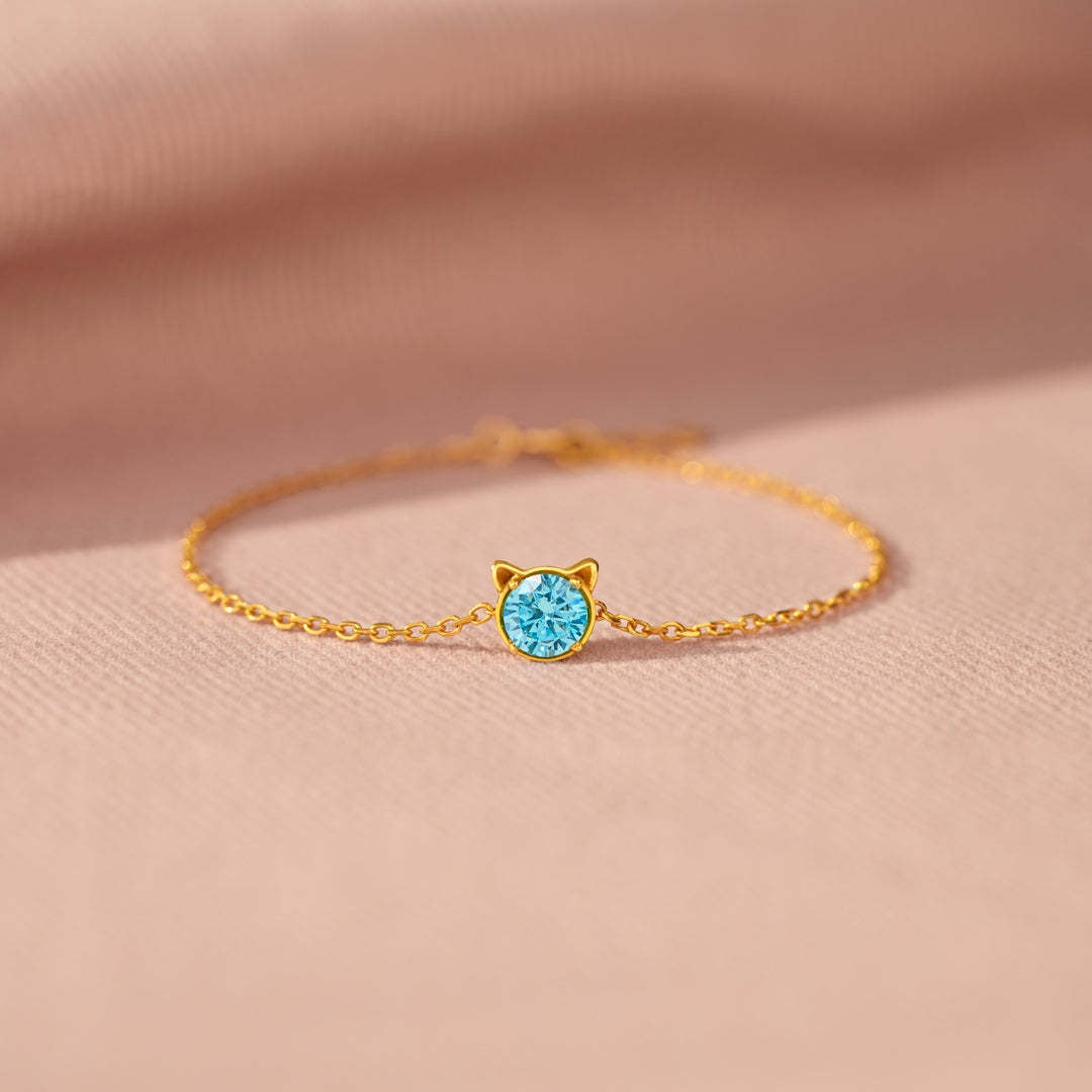 A delicate 925 sterling silver cat bracelet in a gold tone, featuring a minimalist cat face pendant with a sparkling blue cubic zirconia stone.