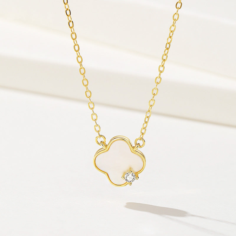 A close-up of a 925 sterling silver four-leaf clover necklace with a gold finish. The pendant is inlaid with mother-of-shell and features a small central gemstone.