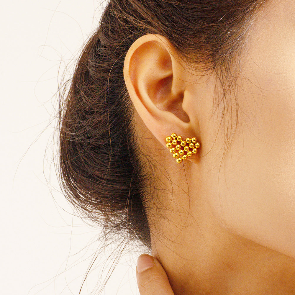 A woman wearing the stainless steel waterproof gold love heart shaped stud earrings, showcasing their elegant look.