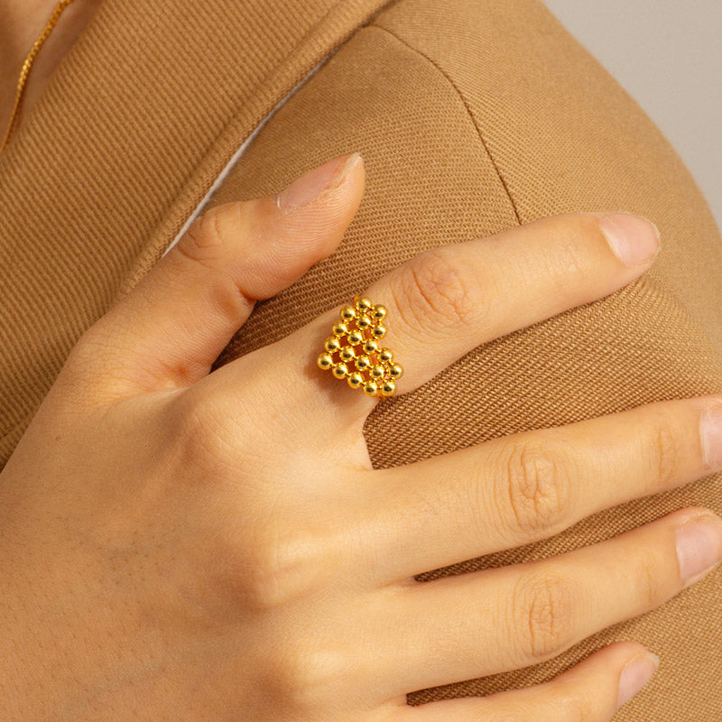 Close-up of a stainless steel adjustable ring with a gold bead cluster design, part of a set of 5.