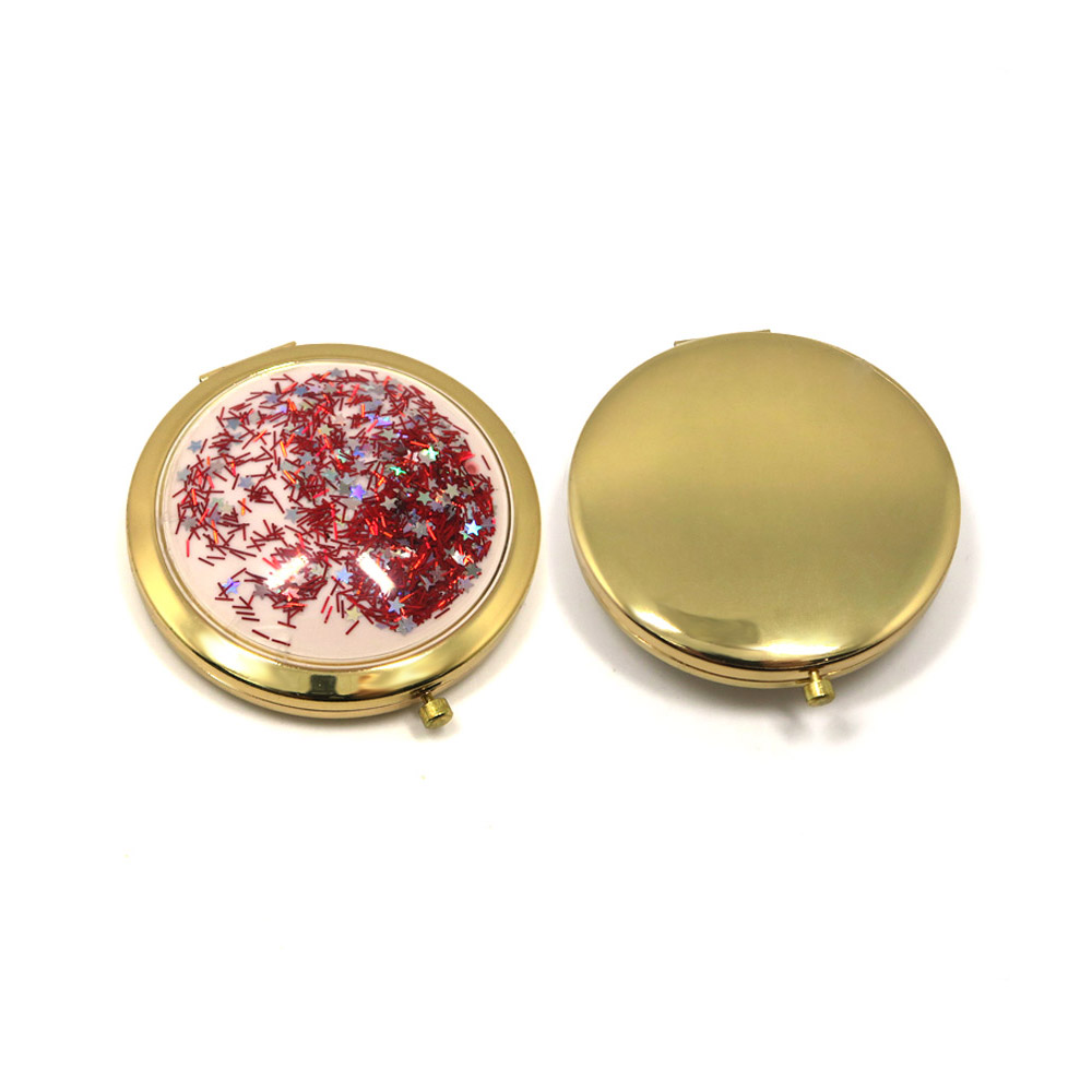 A close-up of the Gold Glitter Crystal Shaker Compact Mirror, showcasing its decorative gold frame and mesmerizing red and silver liquid glitter effect.