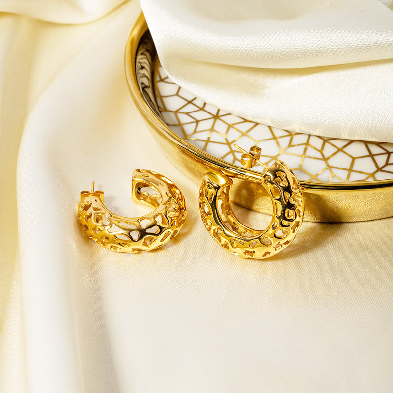 A pair of chunky, gold-plated stainless steel C-shaped stud earrings with a unique textured finish, displayed on a clean background.