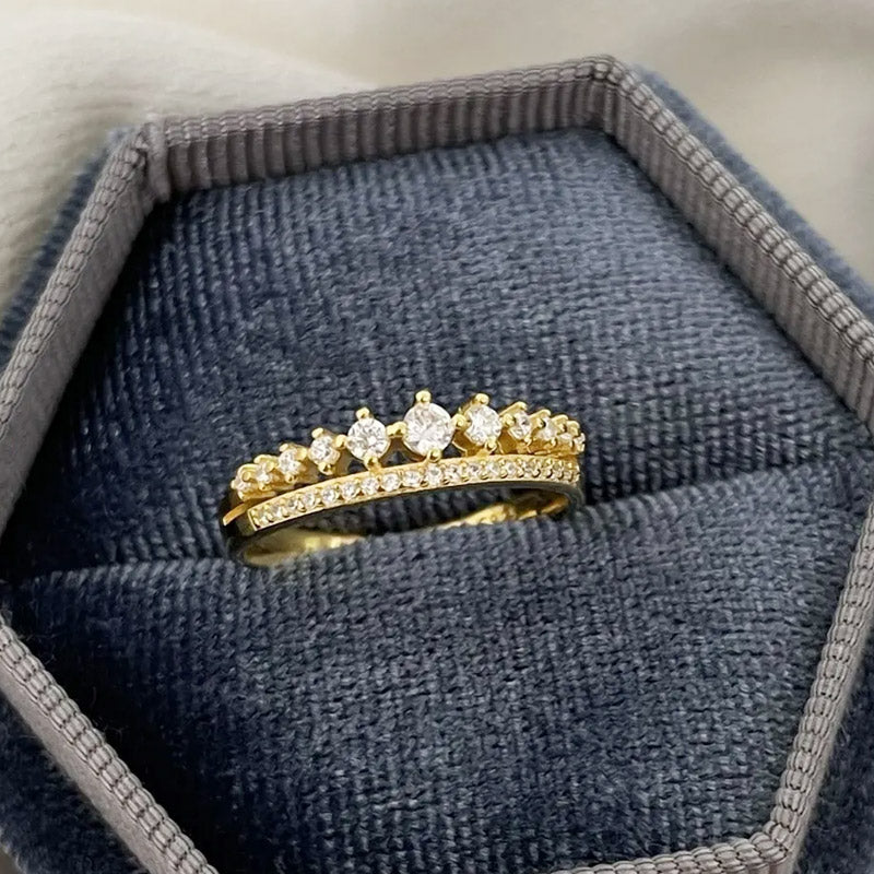 A stunning 925 sterling silver double-row pavé crystal ring with a gold finish, elegantly presented in a dark blue velvet jewelry box.