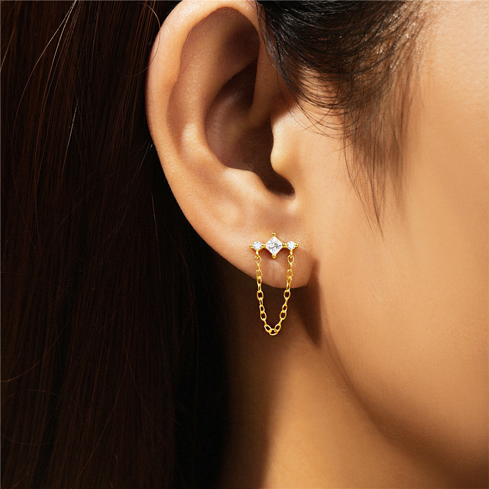 A close-up of a woman wearing a delicate 925 sterling silver gold-plated tassel earring with a sparkling zircon chain element.