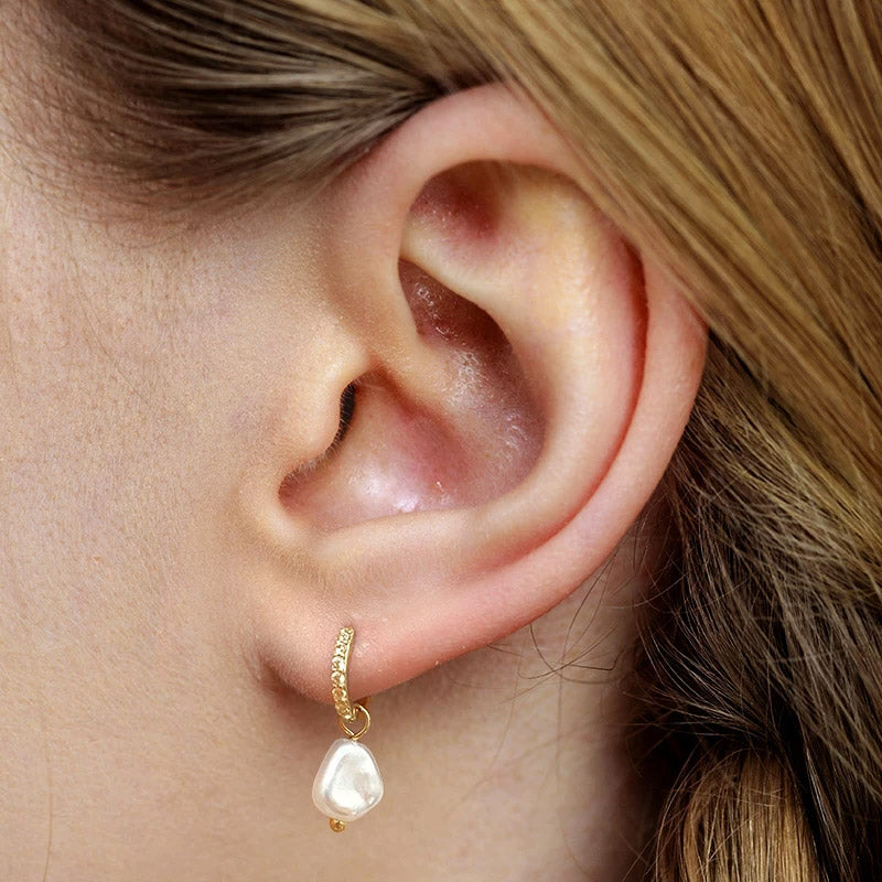 A close-up studio shot of a 925 sterling silver baroque drop earring, featuring a large, irregular white pearl and a sparkling zirconia stone.