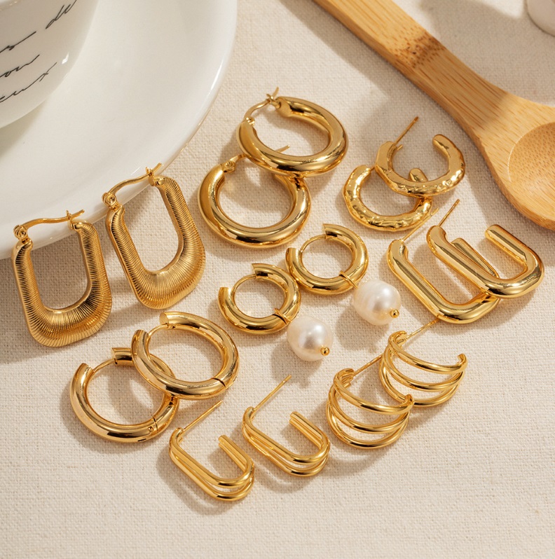 A collection of Stainless Steel 18K Gold Plated Hoop Earrings, showcasing various designs including U-shaped and textured hoops, displayed on a neutral background.