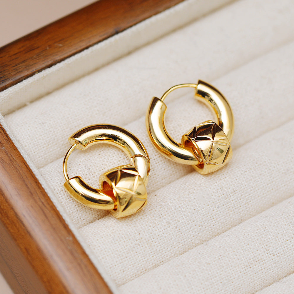 A set of five pairs of vintage gold-plated 20mm huggie hoop earrings displayed elegantly in a jewelry box.