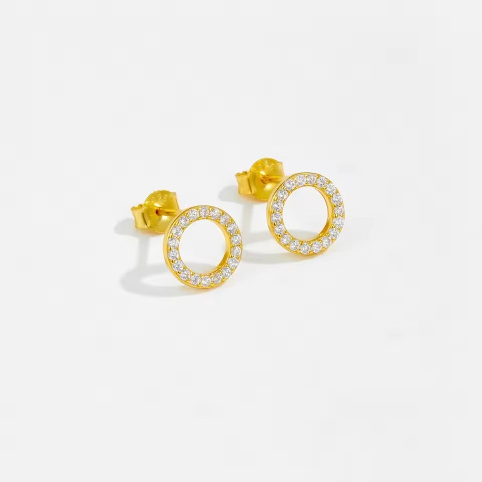 A close-up of S925 gold-plated round stud earrings, showcasing the brilliant cubic zirconia stones set in a classic circular design.
