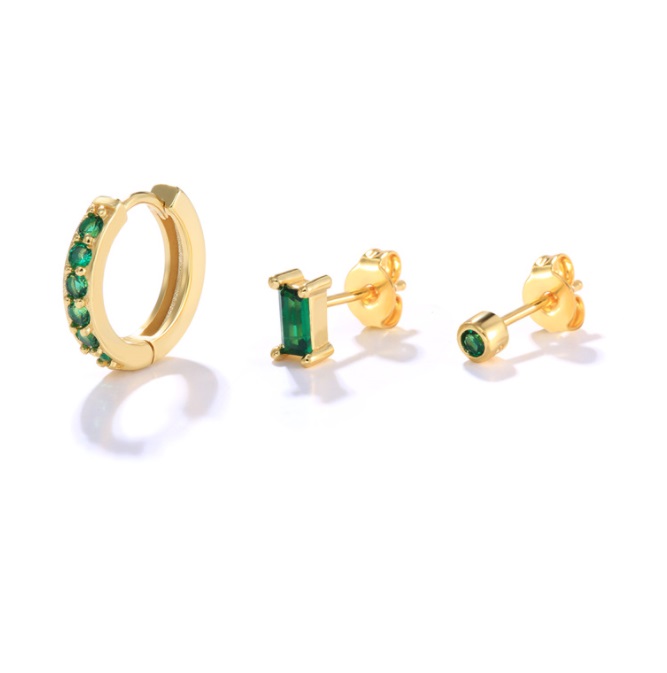 A set of three gold-plated huggie hoop earrings featuring vibrant emerald green cubic zirconia stones, displayed on a clean white background.