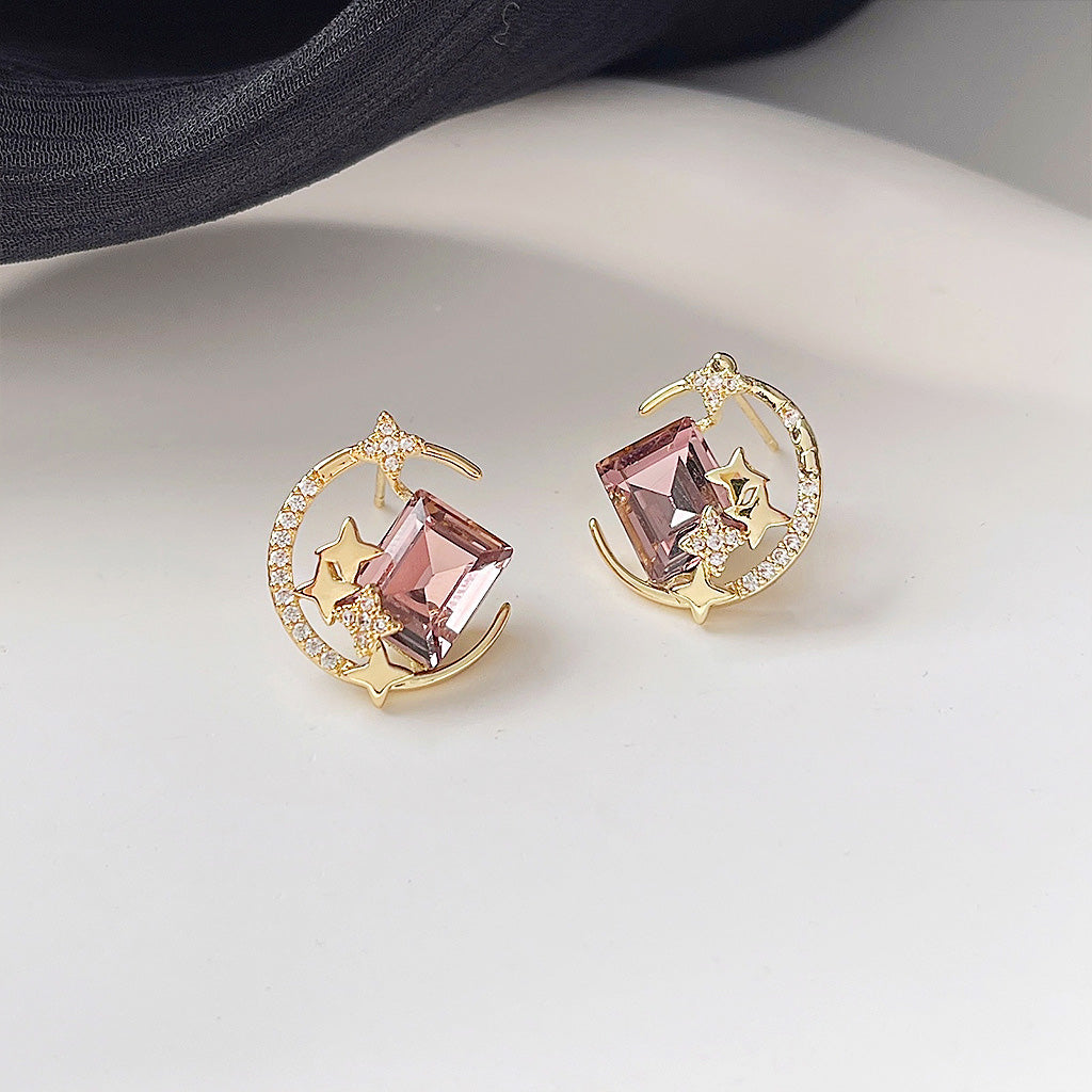A set of five 14k gold-plated moon and star stud earrings with pink glass crystals, displayed on a white surface.