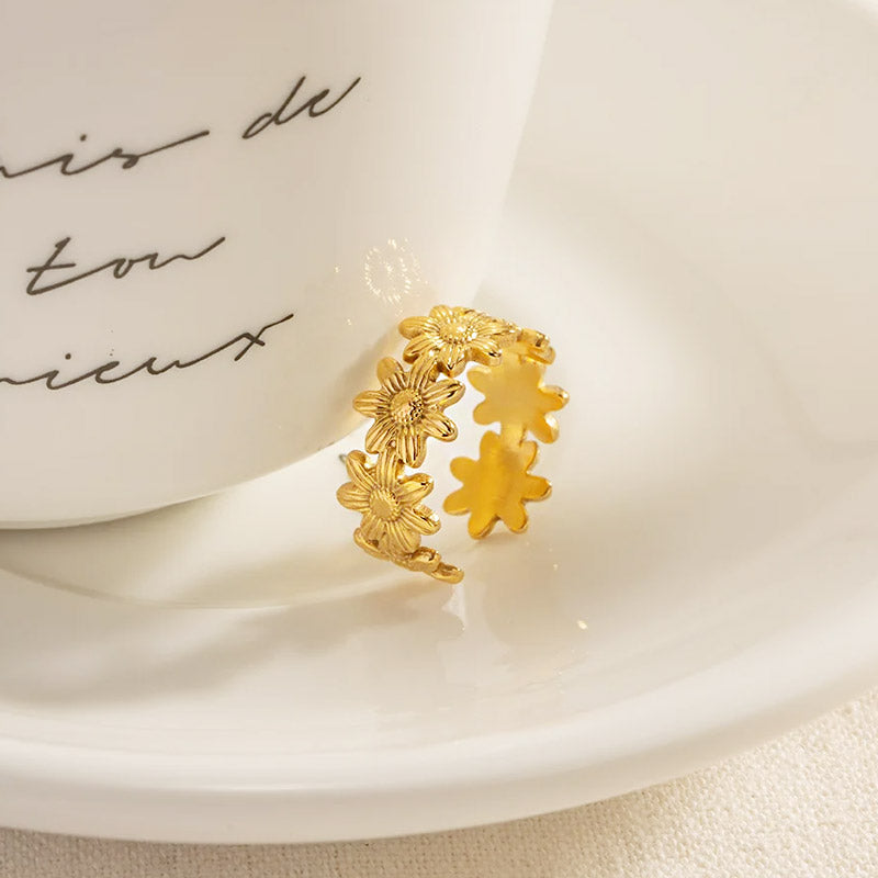 A set of five stainless steel gold sunflower open cuff rings displayed on a clean white background.