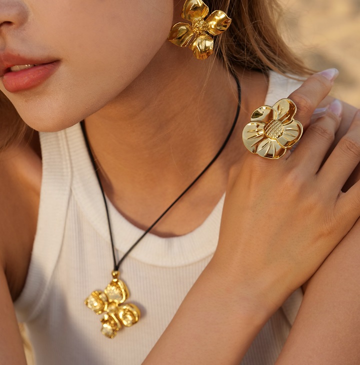 A model showcasing the Stainless Steel 18K Gold Plated Flower Jewelry Set, highlighting the intricate design of the necklace, earrings, and ring.