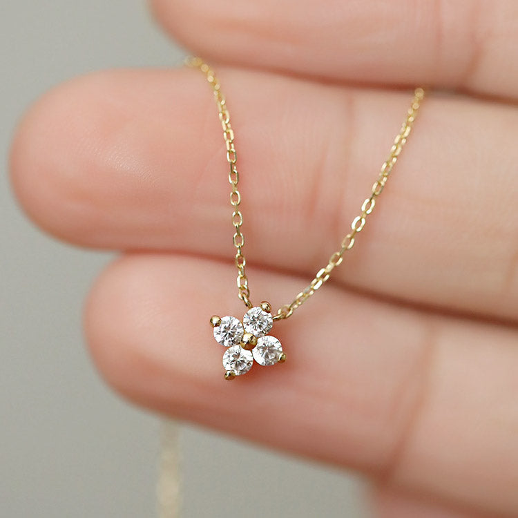 A delicate 925 sterling silver necklace featuring a tiny four-leaf flower pendant adorned with sparkling zircon gemstones.