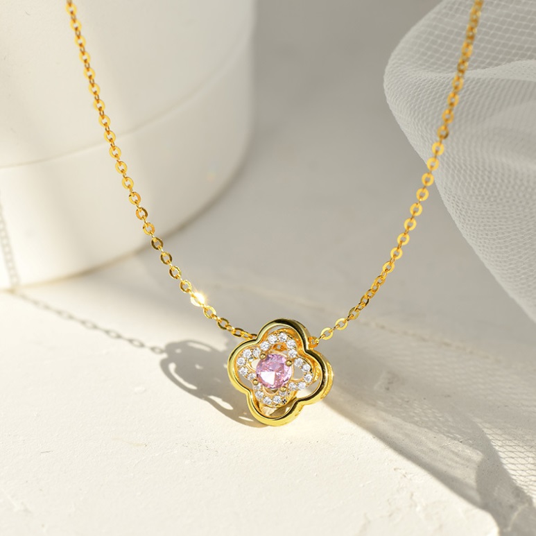 A close-up of the 925 Sterling Silver Clover Leaf Necklace, showing the gold-plated finish and the central pink cubic zirconia stone.