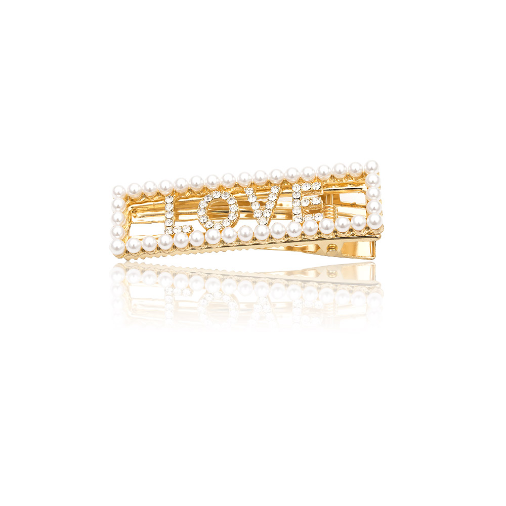 A custom gold hair clip from JR Fashion Accessories, spelling out the word 'LOVE' with inlaid crystal stones, showcasing the personalized word feature.