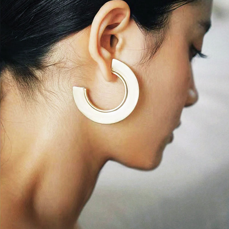 A model wearing the bold brass bohemian punk style geometric C hoop earring in a gold finish, showcasing its size and style.