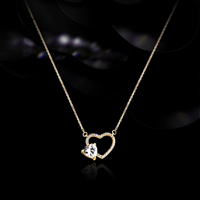 Close-up of a 925 sterling silver necklace with gold plating, featuring a hollow heart pendant with a central heart-shaped zircon stone.