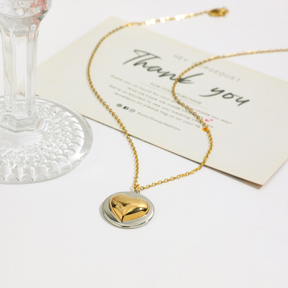 Wholesale stainless steel two-tone heart pendant necklace with a gold and silver finish, displayed on a neutral background.