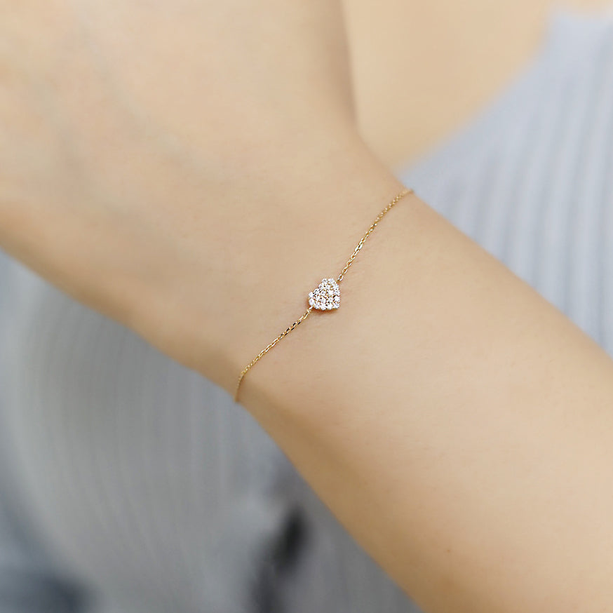 A close-up of a 925 sterling silver bracelet with a gold-pave CZ heart charm, showcasing its intricate details and sparkle.