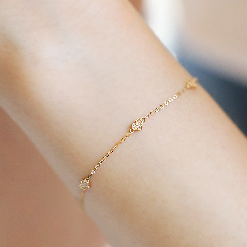 A delicate 925 sterling silver bracelet with a gold-plated finish, featuring a small heart charm, displayed on a white background.