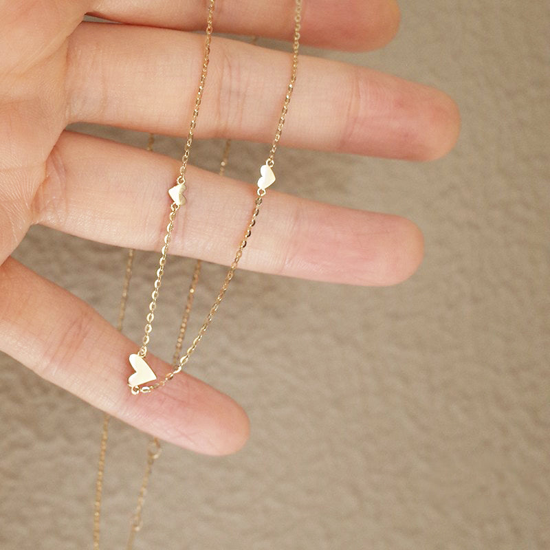 A detailed view of the S925 Sterling Silver Triple Small Heart Necklace, showcasing its delicate triple-heart pendant design in a radiant gold finish.