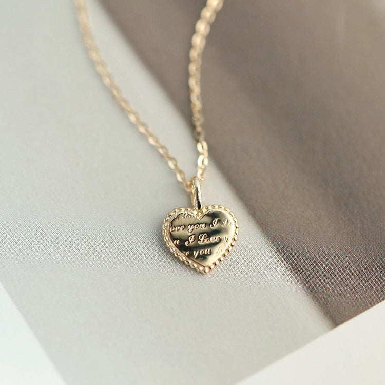 A close-up of the 925 sterling silver gold dainty heart pendant necklace, showcasing the intricate engraved text on the polished heart charm.