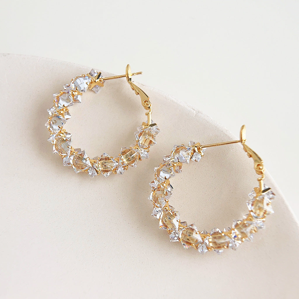 A close-up studio shot of gold-plated hoop earrings adorned with sparkling clear crystal zircon stones, presented as a set of five pairs.