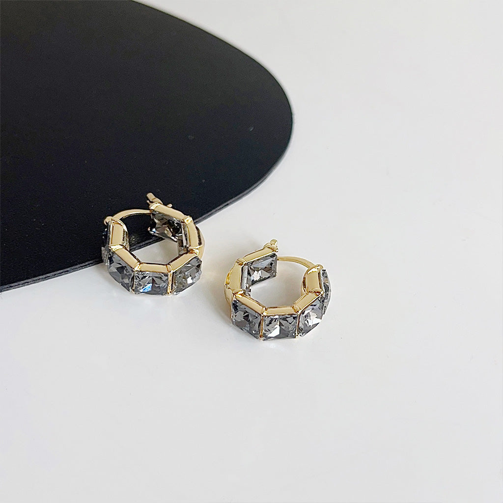 A close-up of gold-plated crystal cube hoop earrings with clear, sparkling glass rhinestones, showcasing their elegant design.