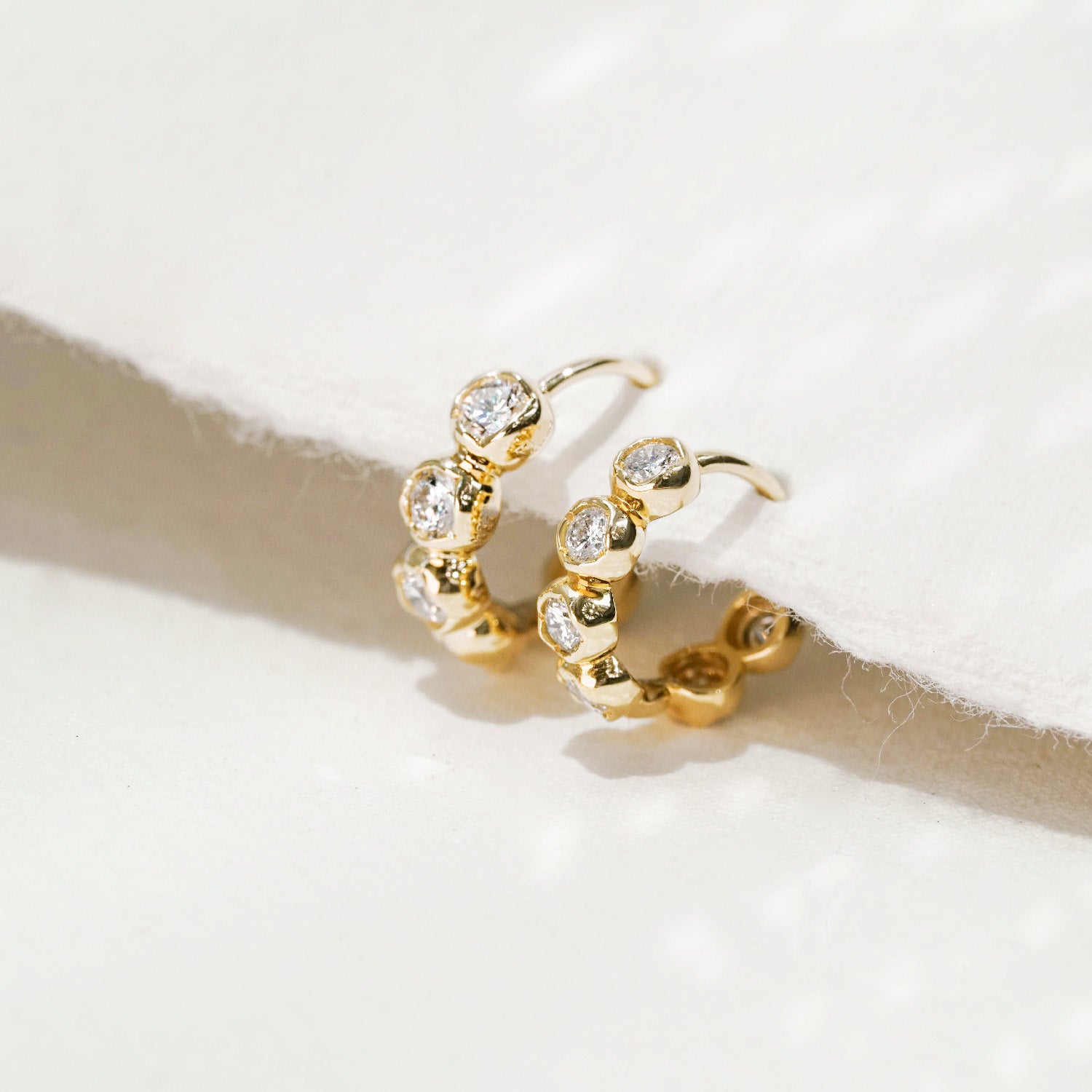 A pair of wholesale 925 sterling silver hoop earrings with sparkling bezel-set cubic zirconia stones, displayed on a clean white background.