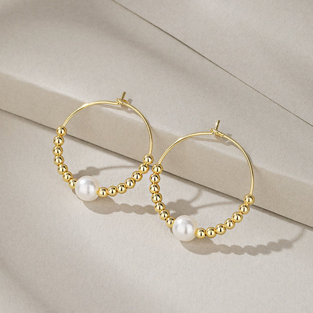 A pair of elegant 925 sterling silver hoop earrings with a gold finish, adorned with a central pearl and delicate gold beads.