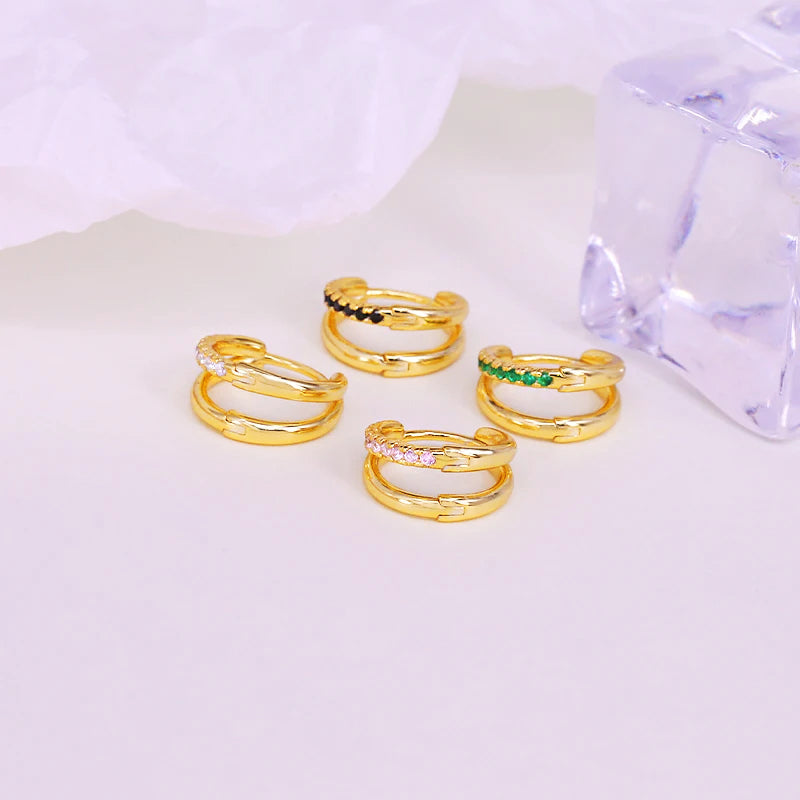 A collection of 925 sterling silver double-circle cartilage hoop earrings in a gold finish, showcasing various stone color options including white, black, pink, and green.