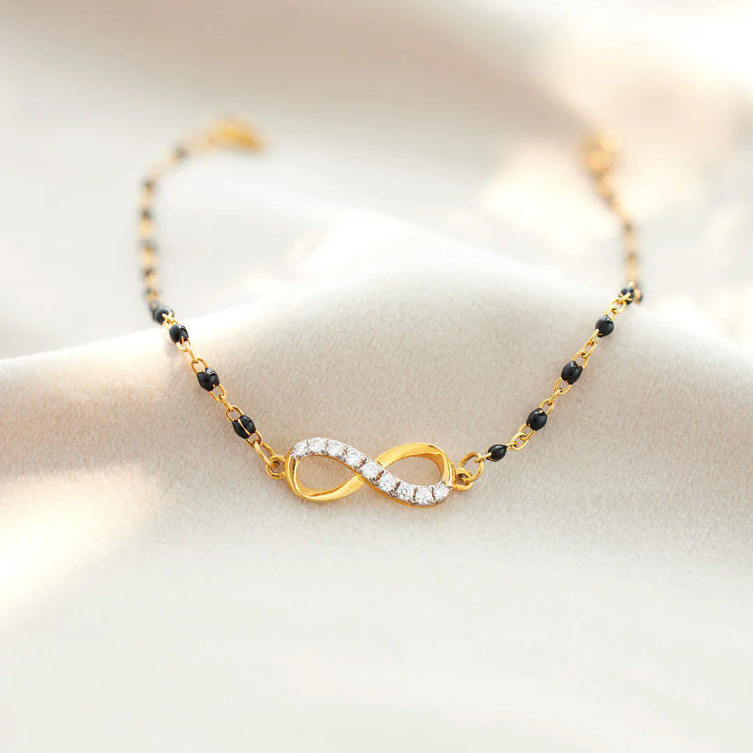 Close-up of the Infinity of Hope bracelet, showcasing the gold-plated infinity symbol with zircon stones and elegant black beads on a 925 sterling silver chain.