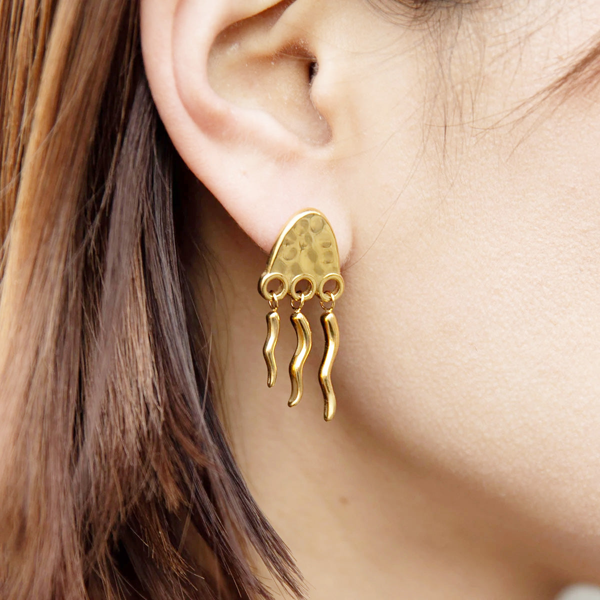 A woman wearing the elegant stainless steel waterproof jellyfish fringed stud earring, showcasing its design and fit.