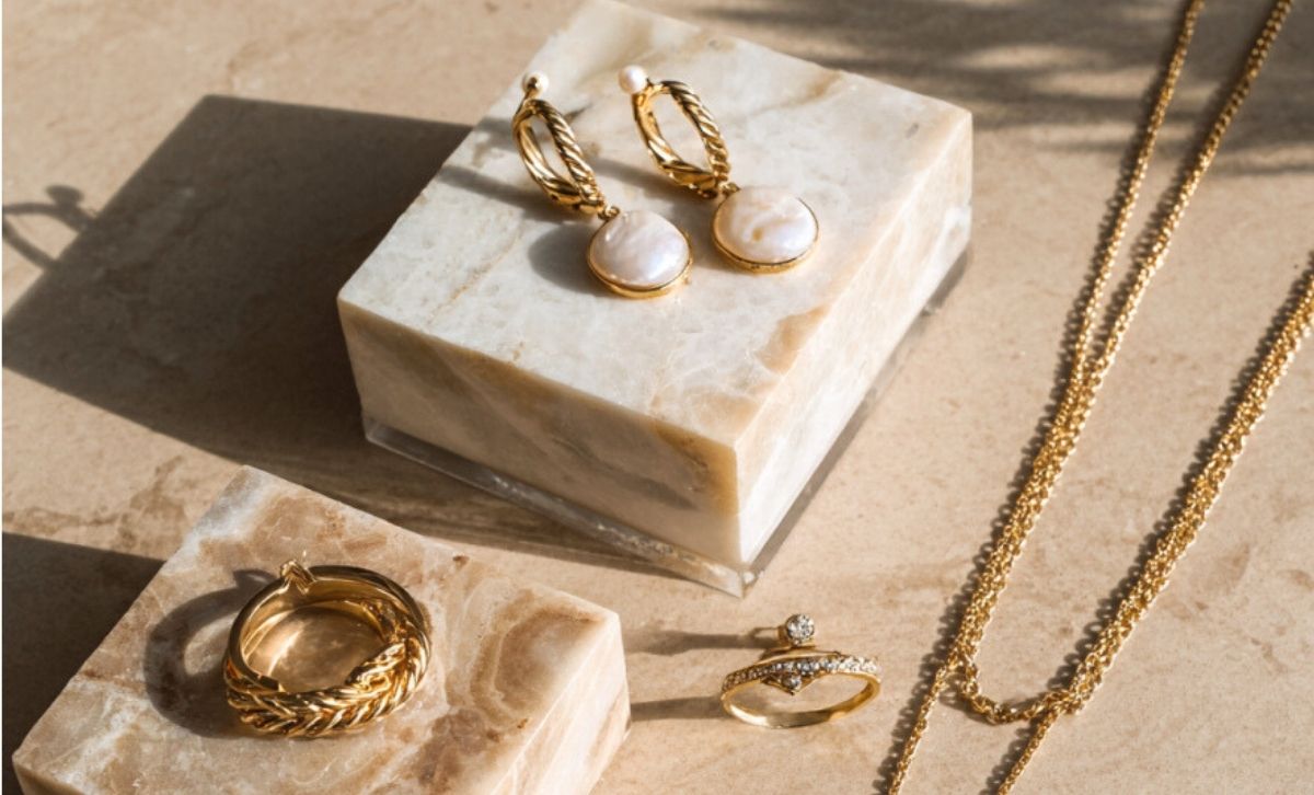 A collection of ion-plated stainless steel jewelry, including gold-finished pearl earrings and rings, demonstrating its waterproof and hypoallergenic qualities.